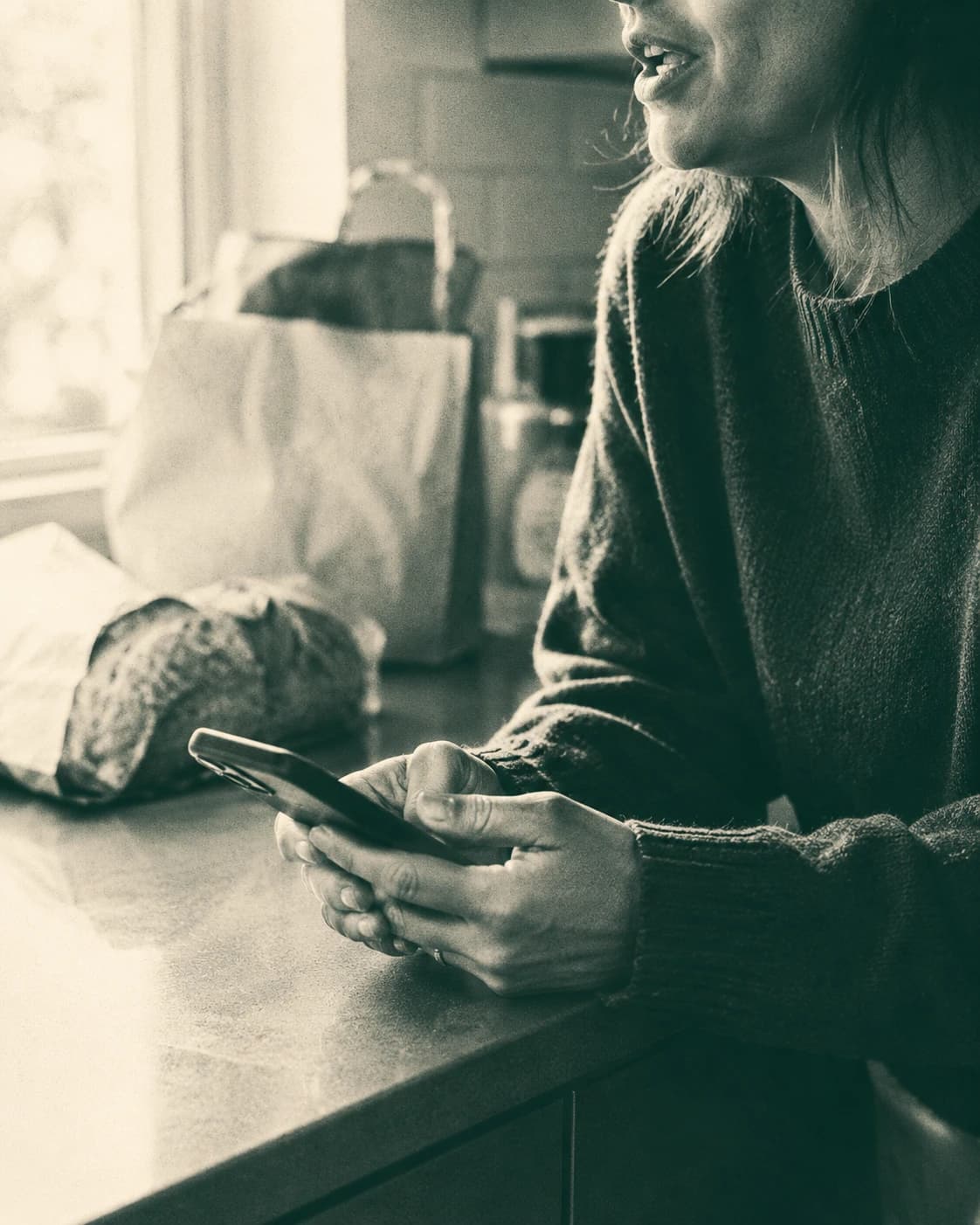 A hand holding a phone at the kitchen table after the weekly shop